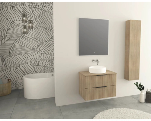 Badrum med tvättställ, spegel, högskåp och badkar framför bladmustertapet