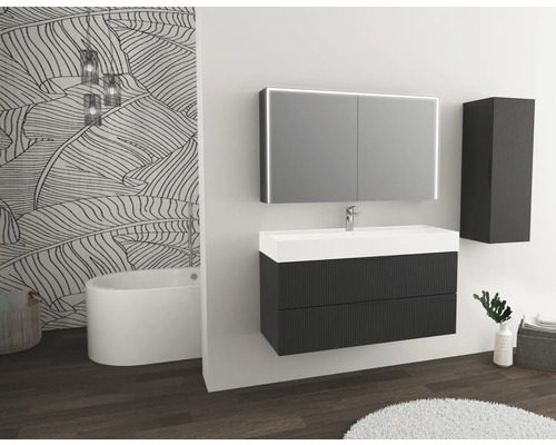 Modernt badrum med tvättställ, spegel, hängskåp och badkar.