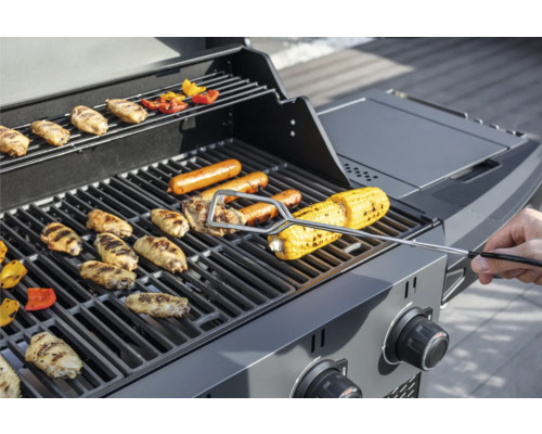Gasolgrill med kycklingvingar, korvar och majskolvar på grillgallret