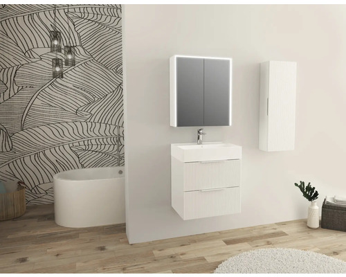 Ljust badrum med tvättställsskåp, spegelskåp, hängande skåp och badkar mot en vägg med bladmönster.