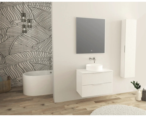 Modernt badrum med tvättställ, spegel, väggskåp och fristående badkar framför en vägg med bladmotiv.