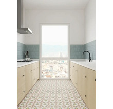 Ljust kök med köksutrustning, fönster och mönstrade golvplattor.