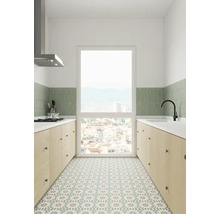 Ljust kök med bänkskivor, diskho, köksfläkt och mönstrade golvplattor.