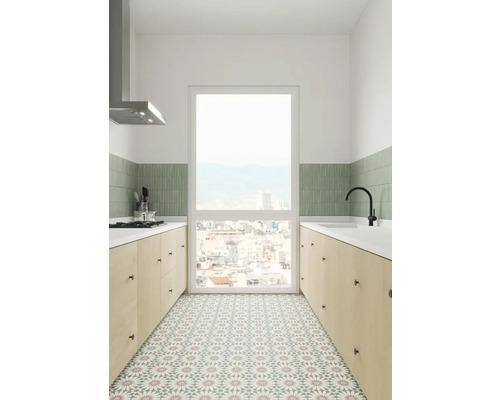 Ljust kök med bänkskivor, diskho, köksfläkt och mönstrade golvplattor.