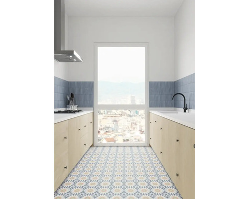 Ljust kök med köksbänk, mönstrade golvplattor och stort fönster