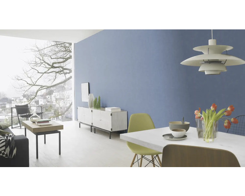 Ljust vardagsrum med blå vägg, matbord, stolar, skänk och stort fönster