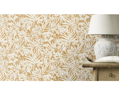 Närbild av en vägg med botanisk tapet som delvis döljer en lampa och en trämöbel.