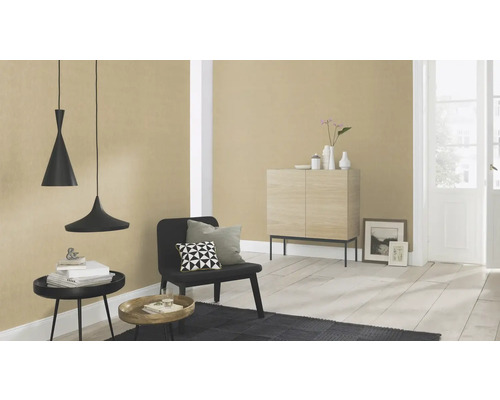 Vardagsrum med hänglampor, stol, matta och byrå mot en tapetserad vägg