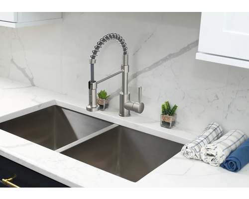 Diskho i rostfritt stål med blandare och diskhanddukar på en bänkskiva i marmor.