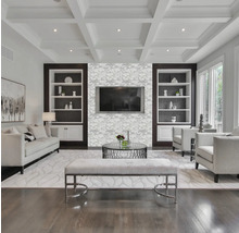 Ljust vardagsrum med soffa, fåtöljer, soffbord, bänk och inbyggda hyllor