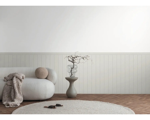 Ljus interiör med soffa, sidobord och dekorativa element mot en väggpanel.