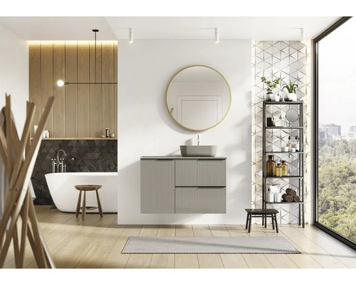 Ljust badrum med badkar, handfat, spegel och hylla