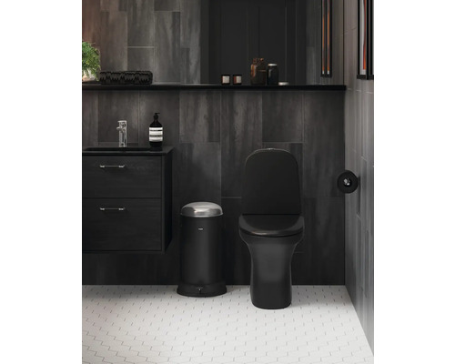 Modernt badrum med svart toalett, papperskorg och tvättställ