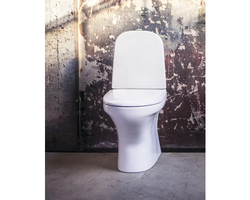 Vit golvstående toalett framför en vägg