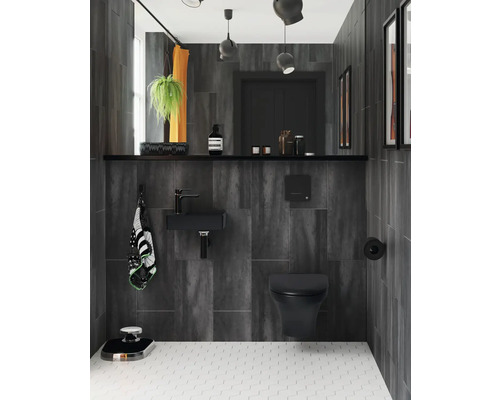 Modernt badrum med mörka väggplattor, handfat, toalett och vitt golv