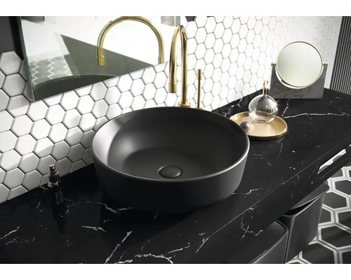 Tvättställ på bänkskiva i badrum med armatur, spegel och hexagonala plattor