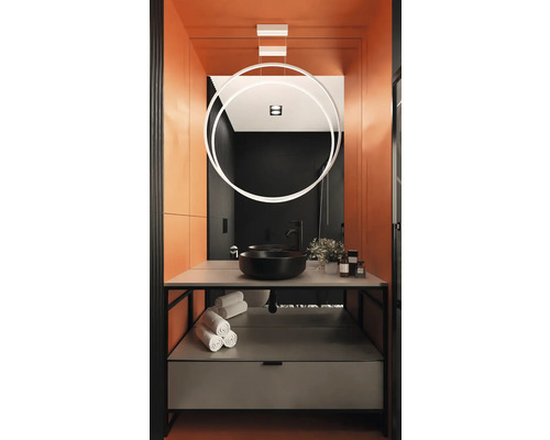 Modernt badrum med svart handfat, handdukar och cirkelformad lampa