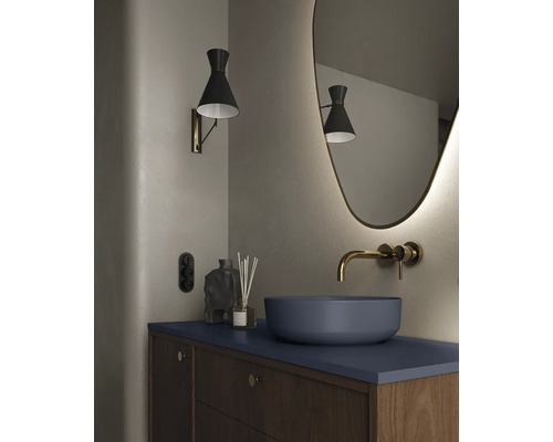 Modernt badrum med tvättställsskål, väggmonterad armatur, belyst spegel och vägglampa.