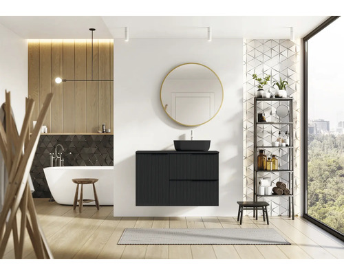 Modernt badrum med svart tvättställsskåp, spegel, badkar och hylla.