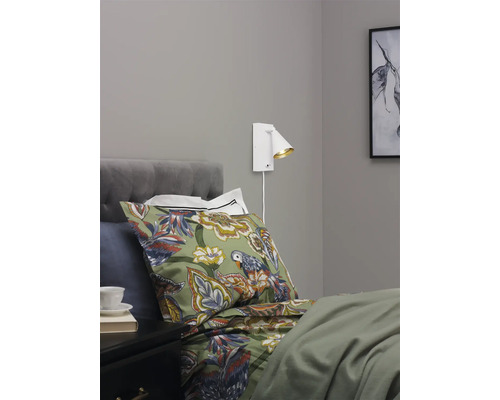 Sovrum med säng, sängbord och monterad vägglampa