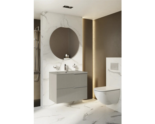 Modernt badrum med tvättställsskåp, rund spegel och vägghängd toalett.