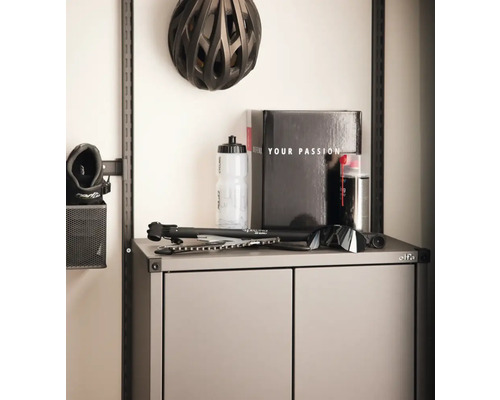 Organiserat förvaringssystem med cykelhjälm, vattenflaska och tillbehör på ett skåp.