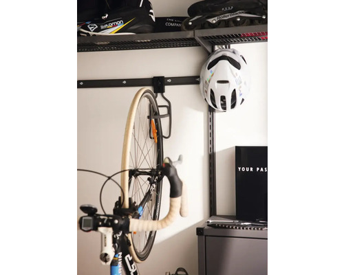 Cykel på väggfäste i ett organiserat rum med hyllor för sportartiklar.