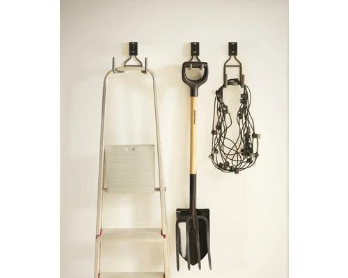 Förvaring av trädgårdsredskap och en stege på en vägg med väggkrokar.