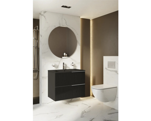 Badrum med svart tvättställsskåp, rund spegel och vägghängd toalett.