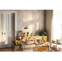 Ljus matplats med träbord, stolar, skänk och blommig tapet för en vänlig atmosfär.