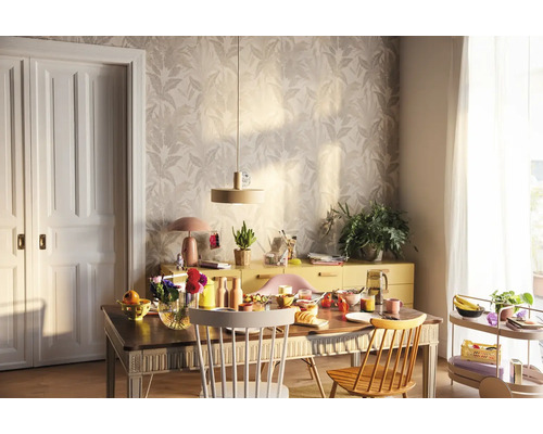 Ljus matplats med träbord, stolar, skänk och blommig tapet för en vänlig atmosfär.