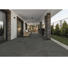 Täckt terrass med mörka golvplattor och tegelkolonner.