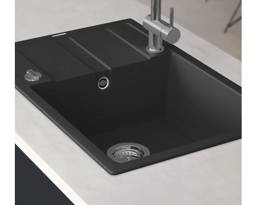 Svart diskho med avrinningsyta och armatur på en bänkskiva