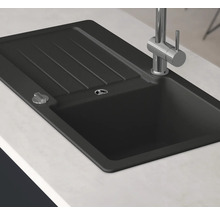 Svart diskho med avrinningsyta och kran på en bänkskiva