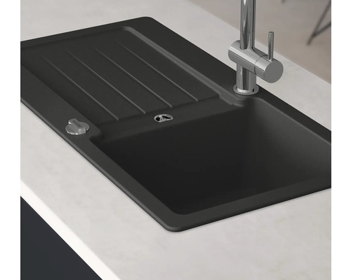 Svart diskho med avrinningsyta och kran på en bänkskiva