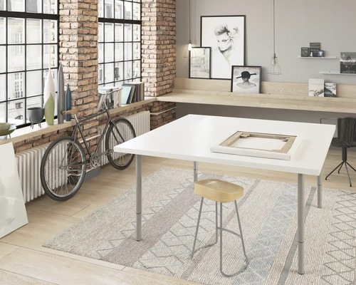 Ateljé med vitt bord, pall och matta framför tegelvägg