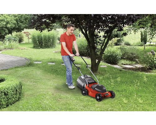 Man klipper gräsmattan med en gräsklippare i trädgården.