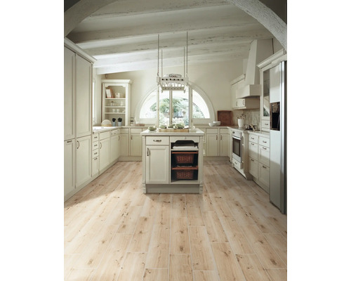 Ljust lantligt kök med köksö, inbyggda skåp och trägolv.