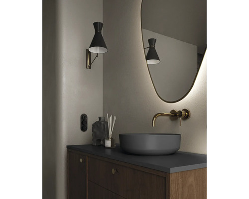 Badrum med tvättställsskål, väggmonterad blandare, spegel, vägglampa och underskåp