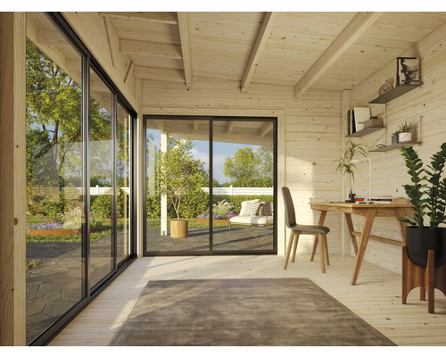 Interiör av ett ljust trädgårdshus med träpanel, stora glasskjutdörrar och en arbetsplats med skrivbord.