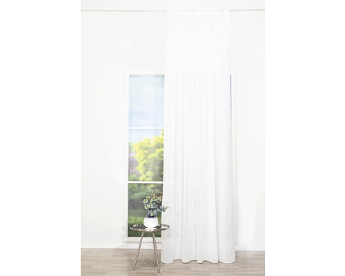 Ljust rum med fönster, vit gardin och ett sidobord med dekoration.