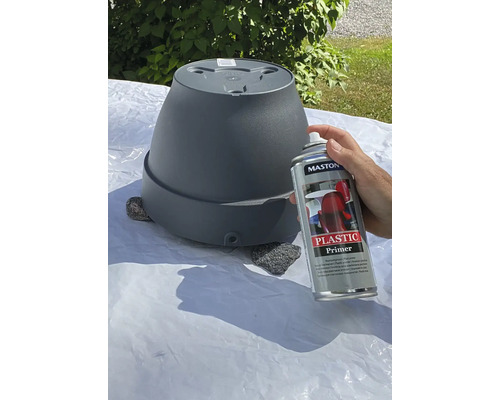 En person sprayar en blomkruka med plastprimer.