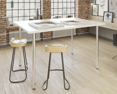 Scen med vitt bord, två stolar, två bildramar och ljust trägolv.