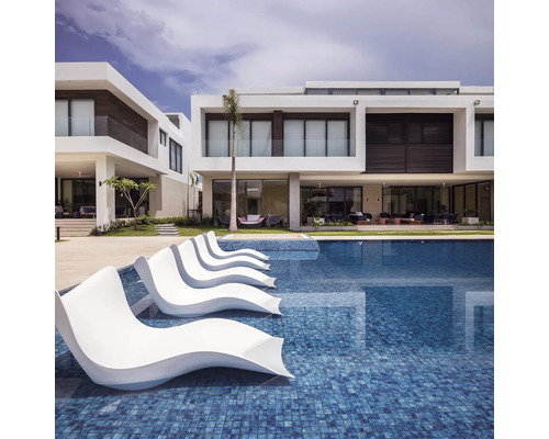 Pool med solstolar och moderna bostadshus i bakgrunden