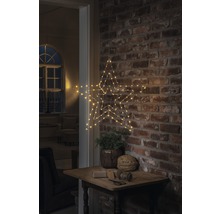 Dekorativ stjärna med LED-belysning, hängande på en tegelvägg ovanför ett litet bord med dekoration.