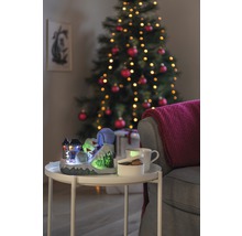 Dekorativ julscen med upplyst skidbacke, kopp, skål och julgran i bakgrunden