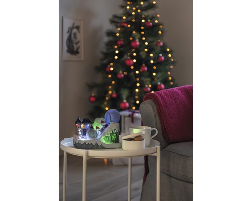 Dekorativ julscen med upplyst skidbacke, kopp, skål och julgran i bakgrunden