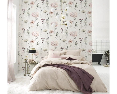 Ljust sovrum med blommig tapet, säng och badkar i bakgrunden