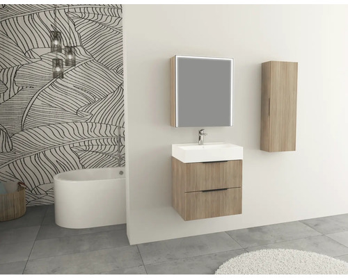 Badrum med tvättställsskåp, spegelskåp och högskåp i träutseende framför en mönstrad tapet