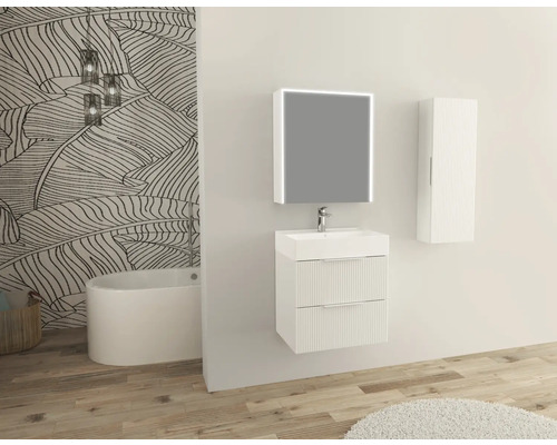 Badrum med tvättställsskåp, spegel, hängande skåp och badkar framför en vägg med bladmönster